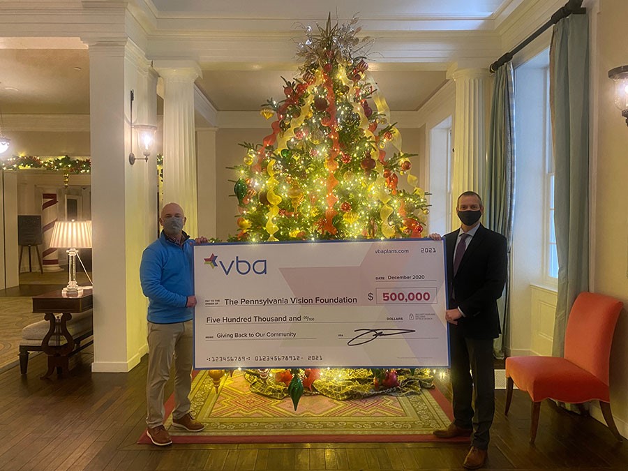 Holding a giant check in front of Christmas tree